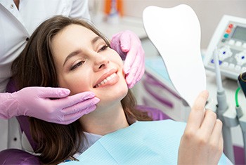 patient smiling while holding dental mirror